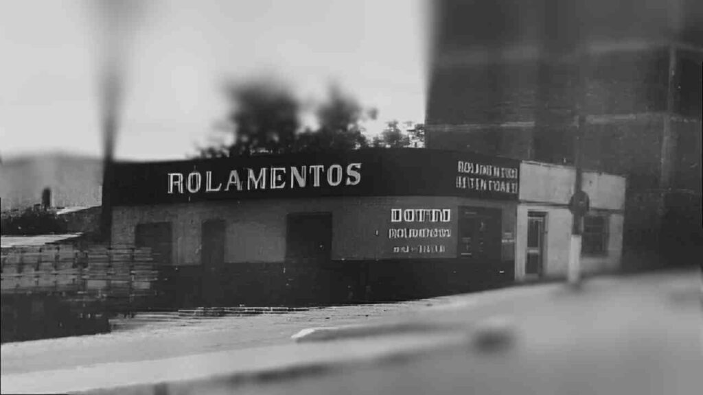 Fachada antiga de uma loja Dotto, que na época se chamava "Rolamentos". A imagem, em preto e branco, mostra o letreiro simples e a entrada da loja.