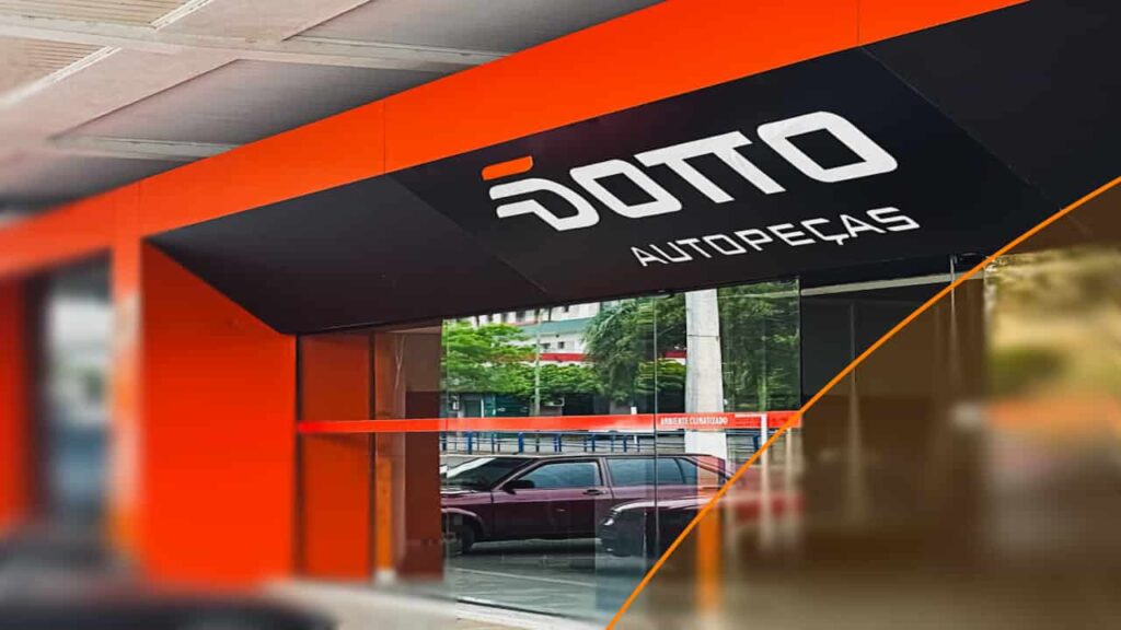 Fachada da loja "DOTTO AUTO PEÇAS", mostrando a entrada e o interior com prateleiras e rodas de carro em exposição na vitrine. As cores da marca, laranja e preto, dominam a fachada.